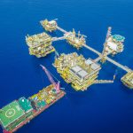 Vista aérea de um complexo de plataformas petrolíferas offshore em alto-mar.