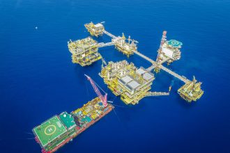 Vista aérea de um complexo de plataformas petrolíferas offshore em alto-mar.