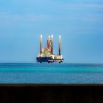Plataforma de petróleo offshore vista à distância em mar calmo sob céu claro.