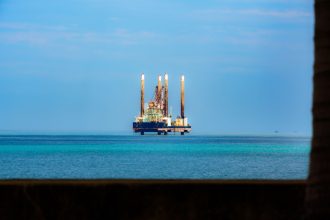 Plataforma de petróleo offshore vista à distância em mar calmo sob céu claro.