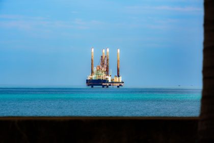 Plataforma de petróleo offshore vista à distância em mar calmo sob céu claro.