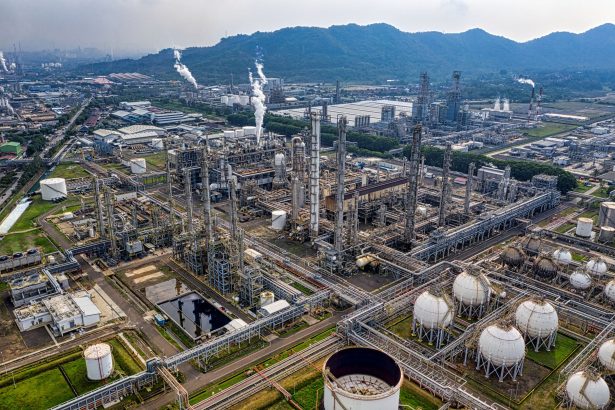 Vista aérea de um complexo de refino de petróleo com tanques de armazenamento e tubulações industriais.