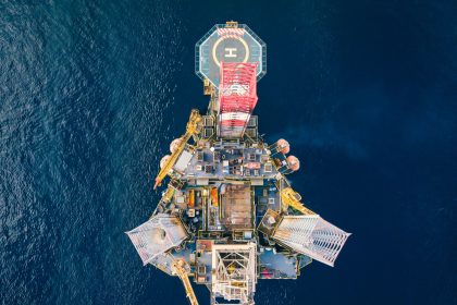 Vista aérea de uma plataforma de petróleo em alto-mar, cercada pelo oceano.