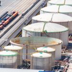 Vista aérea de grandes tanques de armazenamento de combustíveis em um distrito industrial, próximos a linhas ferroviárias