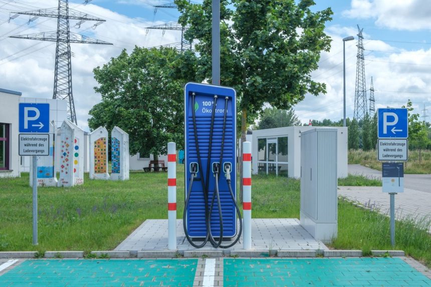 Estação pública de recarga para veículos elétricos em ambiente urbano, com área arborizada ao redor.