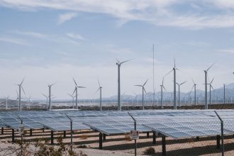 Parque de energia renovável com aerogeradores e painéis solares sob céu aberto.