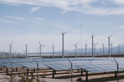 Parque de energia renovável com aerogeradores e painéis solares sob céu aberto.