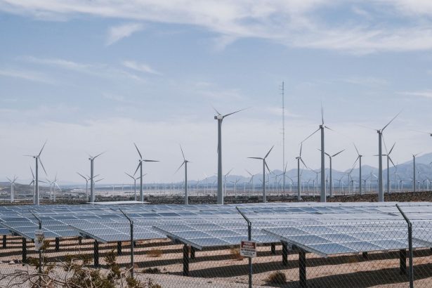 Parque de energia renovável com aerogeradores e painéis solares sob céu aberto.