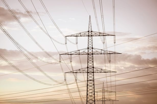 Torres e linhas de transmissão de energia elétrica em silhueta diante de um céu colorido ao entardecer.